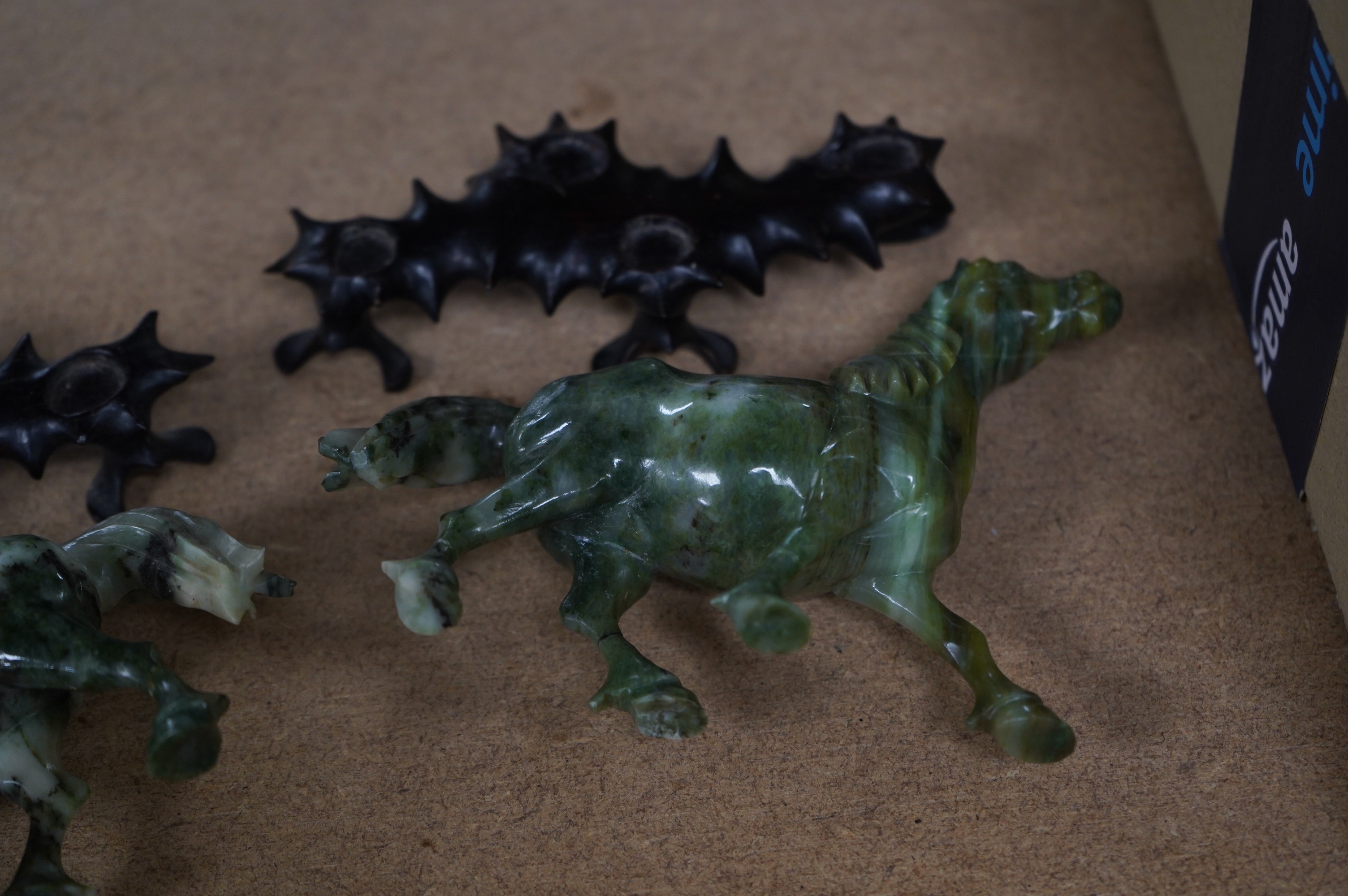 A pair of mid 20th century Chinese jadeite figures of horses, raised on hardwood stands, 13cm wide. Condition - fair, two legs broken and re-glued